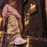 Femme streetwear en hoodie rose poudré et cargo beige doré, look urbain